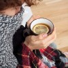 woman who got cold sitting in scarf and blanket holding a cup of tea