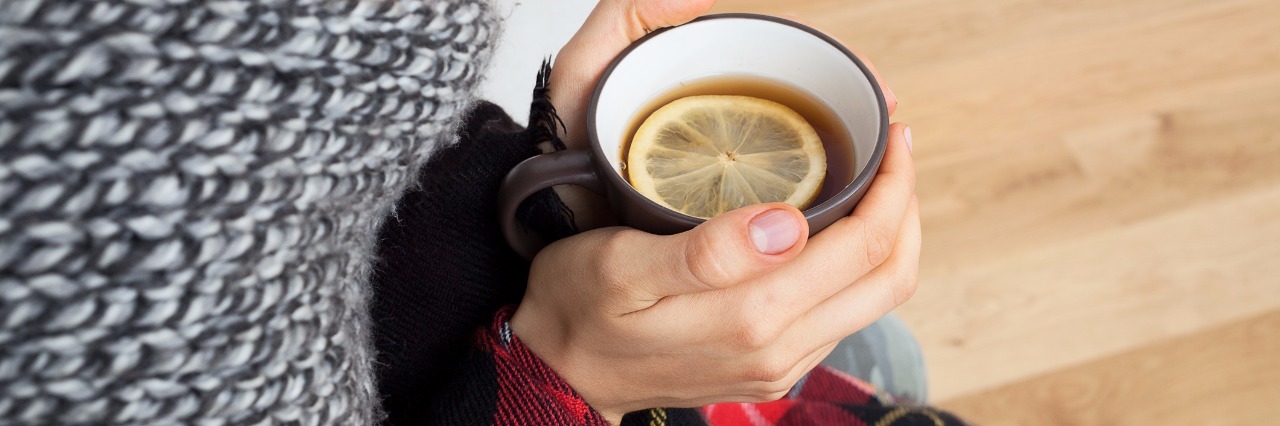 Depression as the 'Common Cold' of Mental Illness woman who got cold sitting in scarf and blanket holding a cup of tea