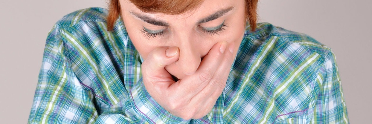 Coping With Emetophobia During Flu Season a woman in a plaid shirt holding her hand over her mouth