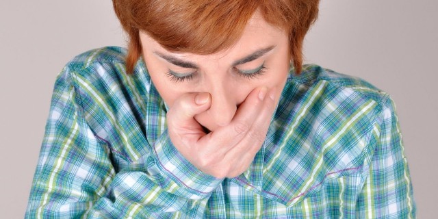 a woman in a plaid shirt holding her hand over her mouth
