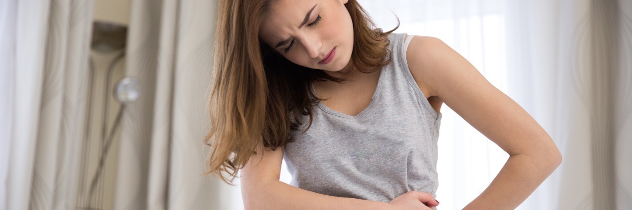 Effects of Stress and Flares of Interstitial Cystitis woman sitting on bed and hunched over in pain