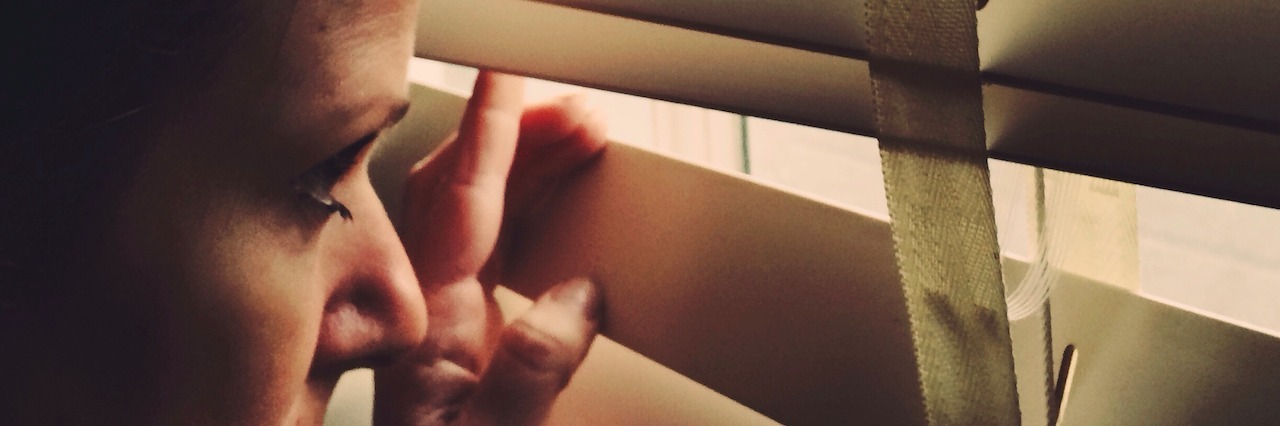 Good Days and Bad Days With Mental Illness A woman looking through blinds on a window