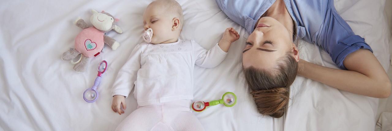 Postpartum Disorders: Why You Don't Have to do It All in Motherhood a mom sleeping in bed with her baby