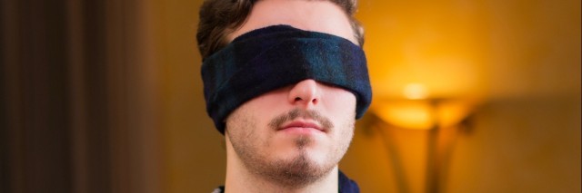 Blindfolded young man at home in living room