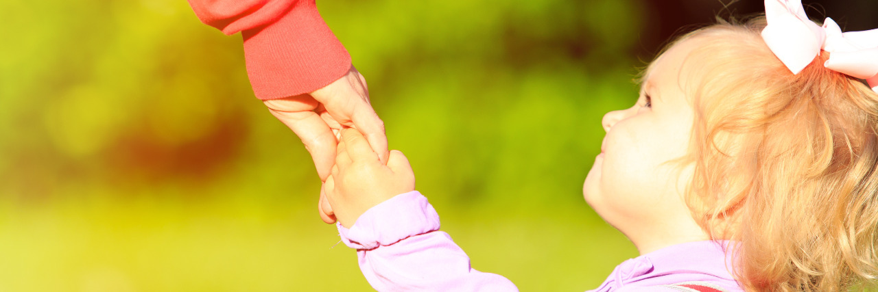 My Young Daughter's Words of Comfort After My Miscarriage Mother holding hand of little daughter outdoors.