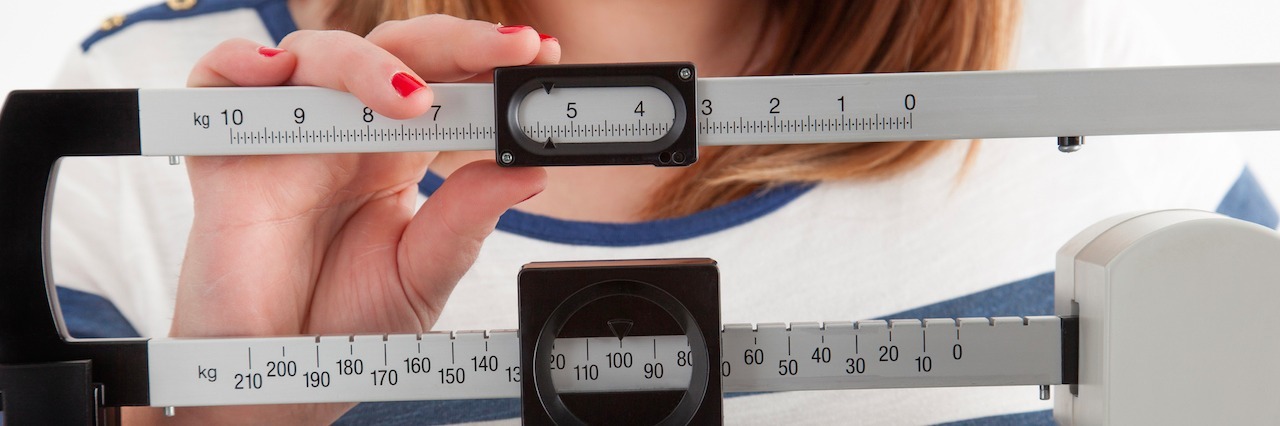 Close-up view of a woman adjusting a medical weight scale