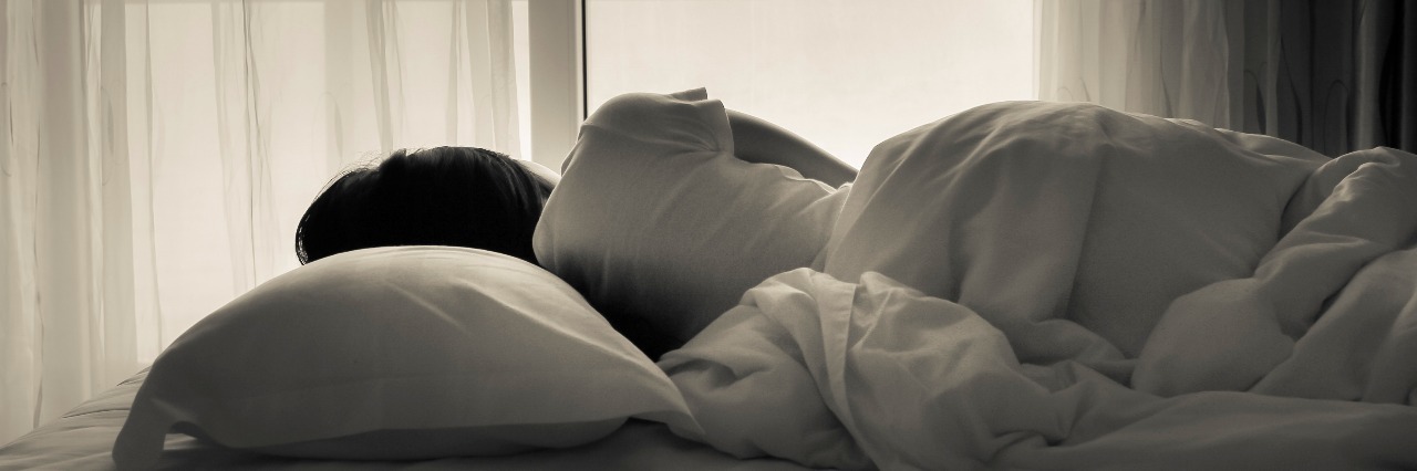 What Mania Looks Like black and white photo of young woman sleeping in bed beside the window