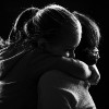 Black and white image of a little girl hugging her mother