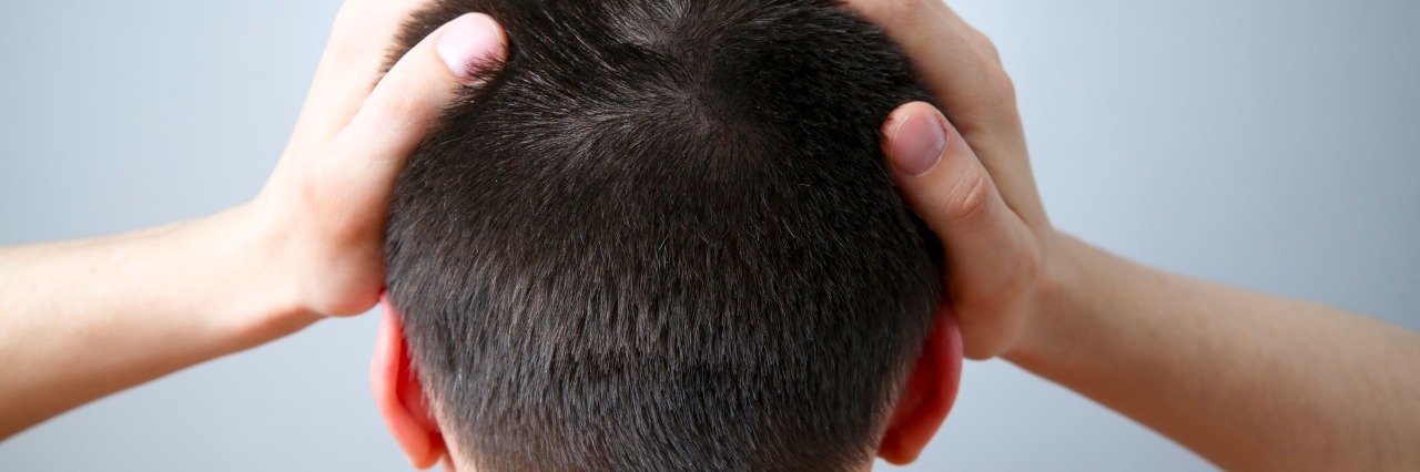 Why People With Migraine Are Awesome rear view of man putting his hands on his head