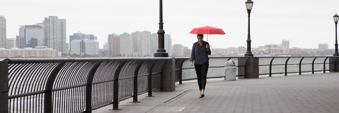 What a Bipolar Disorder Diagnosis Is Not Woman walking on bridge, holding red umbrella