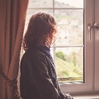 Young woman is looking out the window