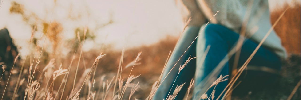 The Social Isolation and Loneliness of Being Chronically Ill Defocused abstract loneliness concept. Cropped feet of lonely young woman sitting on stone. Solitude