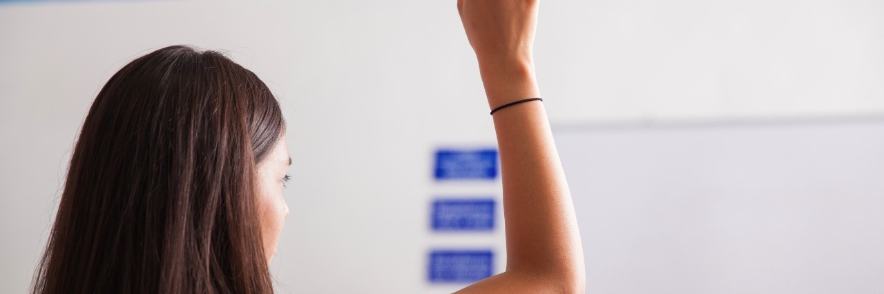 high school student raising her hand to ask a question in class