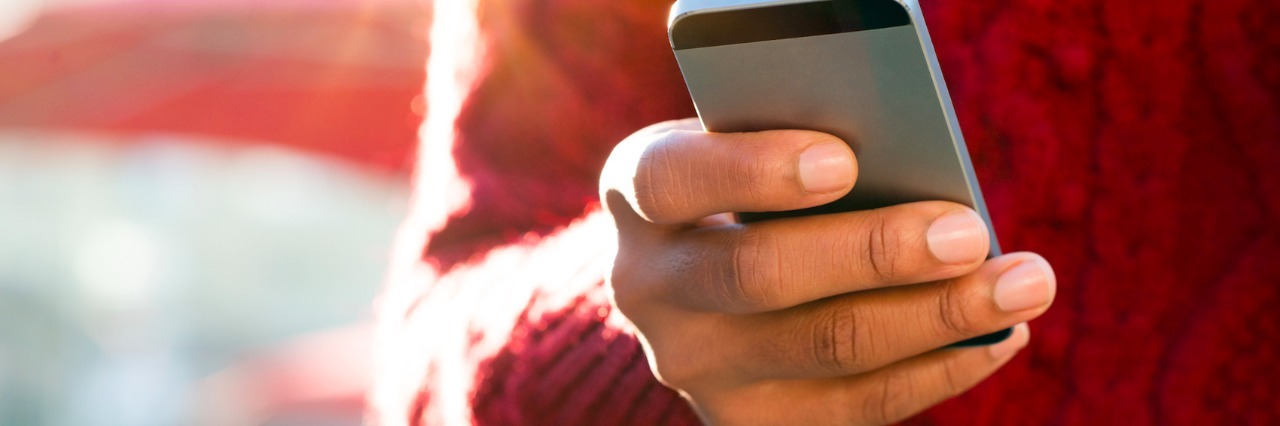 Suggestions for Overcoming FOMO With Invisible Illness Close-up of person wearing red sweater, typing on phone