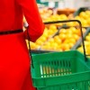 woman holding grocery basket in fruit section of store