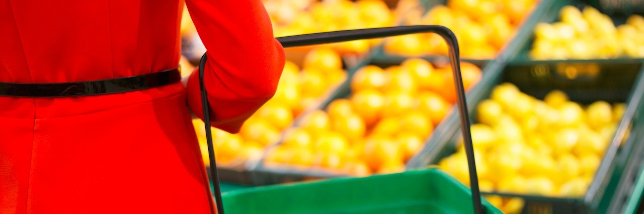Why It's Hard to Grocery Shop With a Diet-Sensitive Illness woman holding grocery basket in fruit section of store