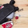 Backpack next to red shoes and glasses on a wood floor
