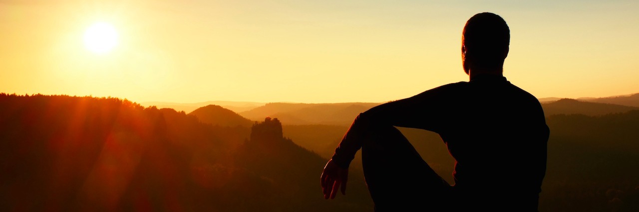 man watching sunrise on mountaintop