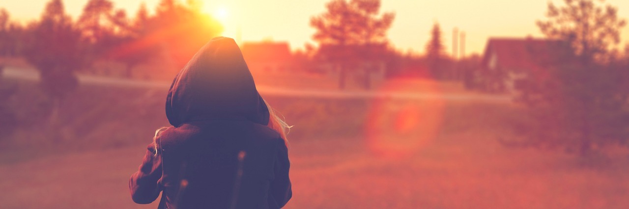 Advice for Chronically Ill Teenagers With Ulcerative Colitis girl wearing hoodie sitting in countryside