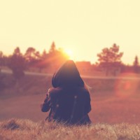 girl wearing hoodie sitting in countryside