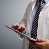 doctor using digital tablet on gray background