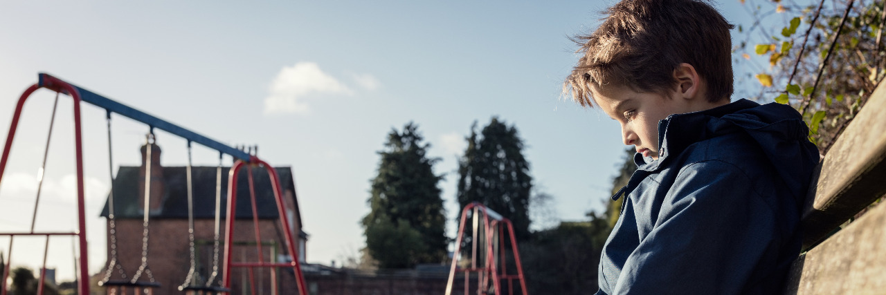Dismissing Bullying as 'Kids Will Be Kids' Hurts Children With Autism Sad child on park bench.
