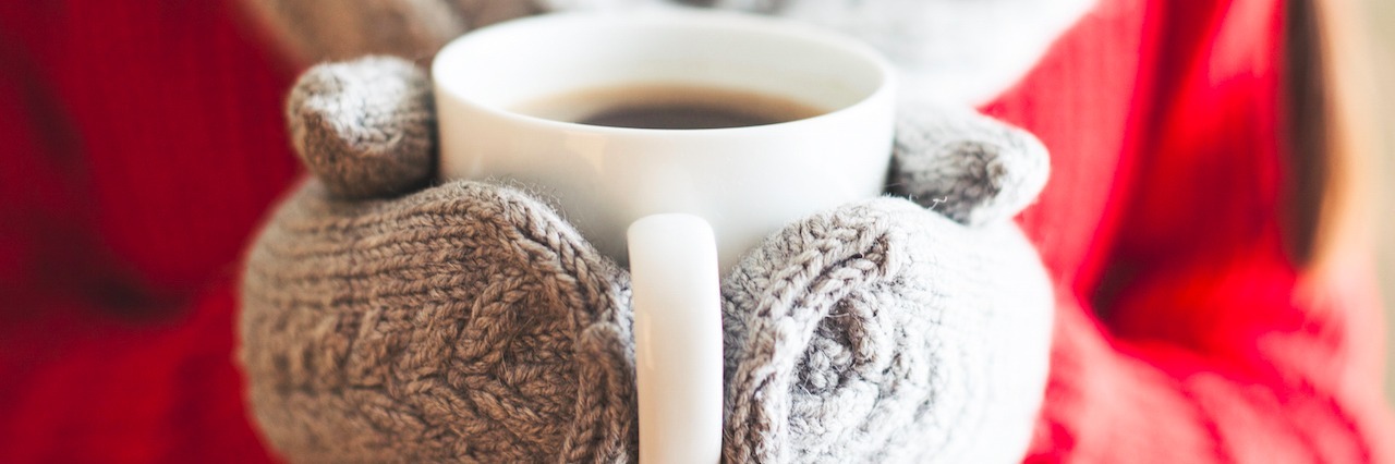 How to Stay Warm in Winter With Lupus Female hands holding hot mug close up. Woman hands in woolen mittens holding a cup with hot cocoa, tea or coffee.