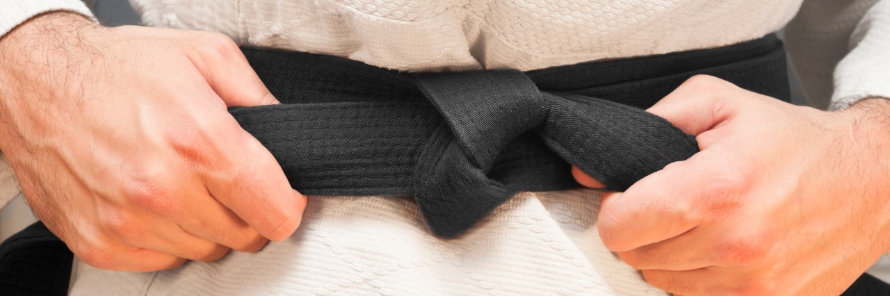 Joint Hypermobility Syndrome, CRPS Affecting Ability to Do Hobbies person wearing a taekwondo outfit and tightening their black belt