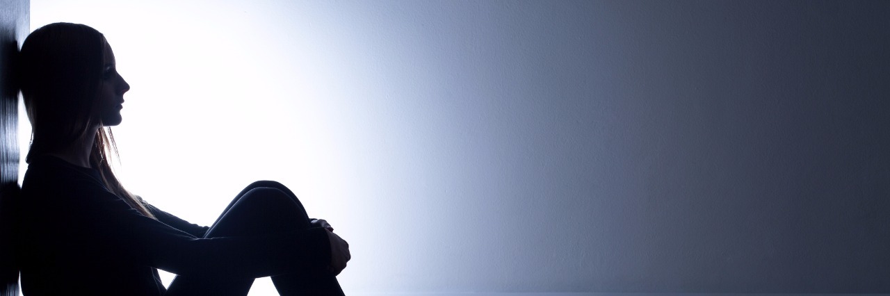 teenage girl with depression sitting alone in dark room