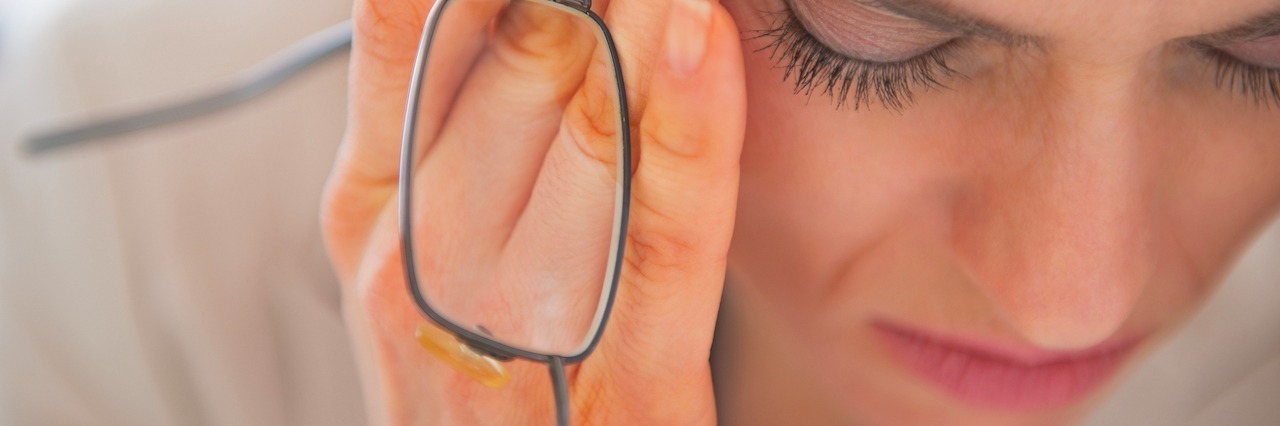 How 'Burnout' Can Negatively Impact Mental Health woman rubbing her eyes, holding glasses