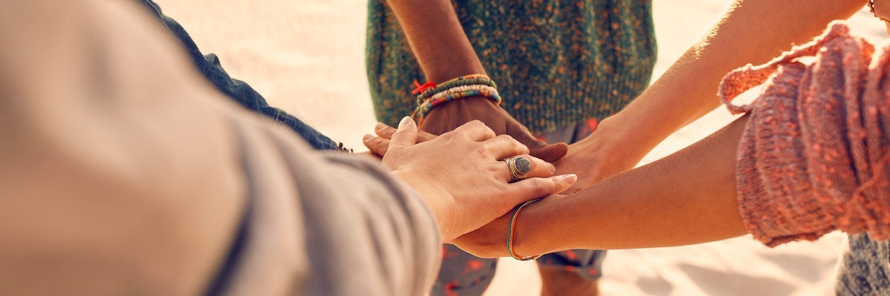 Why Having Friends to Help Fight Depression and Anxiety Is Important group of friends putting their hands together at the beach