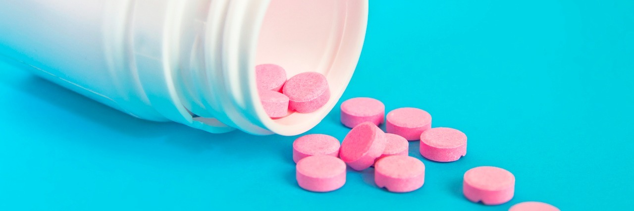 Antidepressant and Yoga Together Help With Depression and Anxiety pills slipping out of a pill bottle