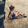 child sitting in parking lot next to mom's car