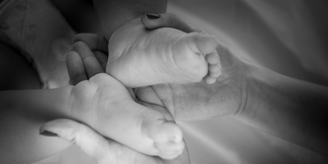 The child's feet in mother's hands in black and white image
