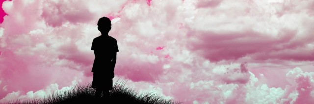silhouette of boy looking at pink sky