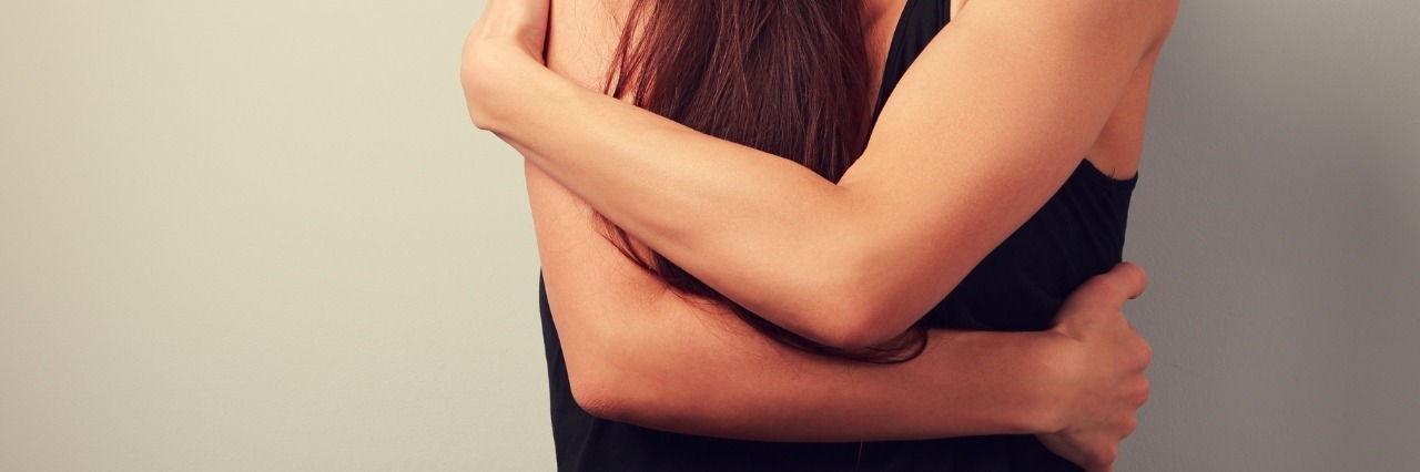 Finding Self-Compassion While Living With Depression a young woman hugging herself