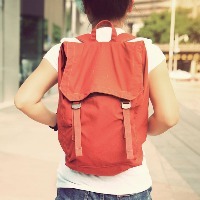 woman walking down street wearing orange backpack