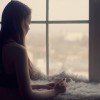 woman holding coffee cup looking out window in the morning