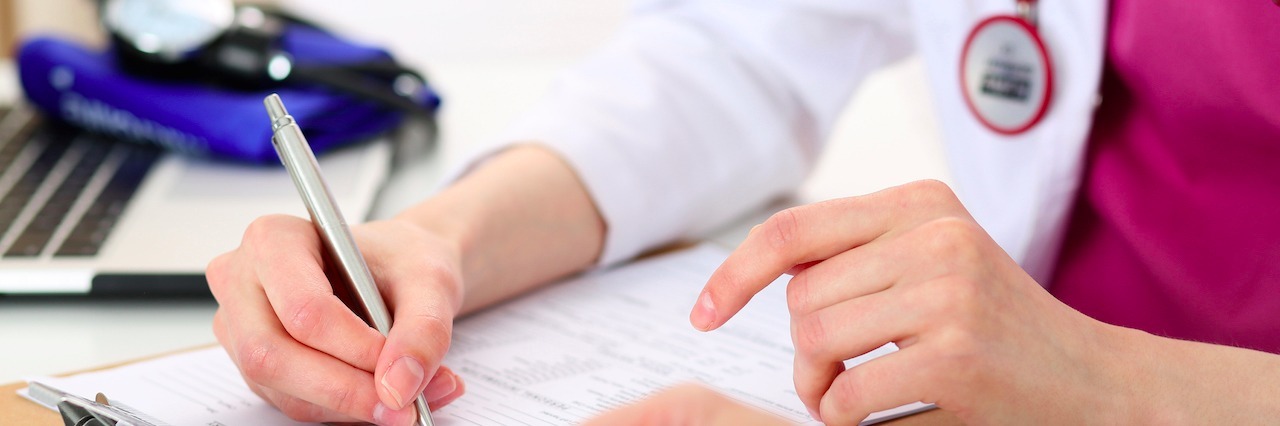 Why Medical System Is Broken for People With Chronic Pain doctor holding pen and signing forms with patient