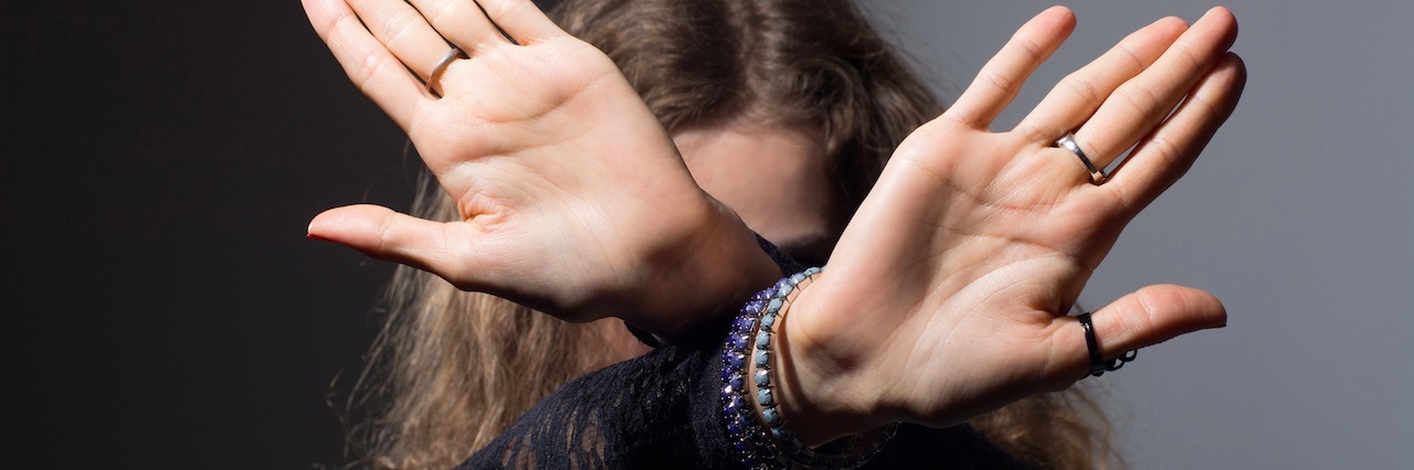 The Worst Assumptions People Make About Living With Eating Disorders woman with her wrists crossed and hands out