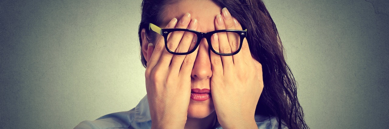 Worst Advice People With Chronic Illness Have Gotten Closeup portrait young woman in glasses covering face eyes using her both hands isolated on gray wall background