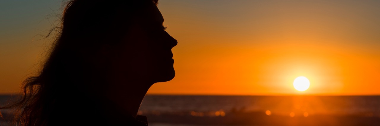September: Suicide Prevention Month and What It Means to Me Silhouette profile of young female during sunset in San Diego pacific ocean beach, California