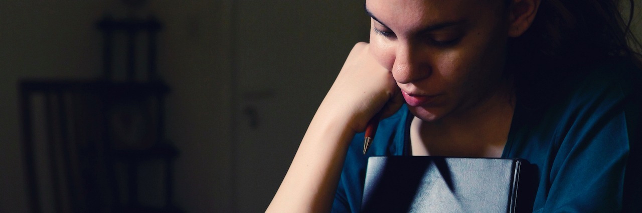 How 'Lack of Motivation' in Depression Affects School Work woman thinking deeply and holding a book