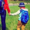 back to school- mother holding hand of little son with backpack outdoors