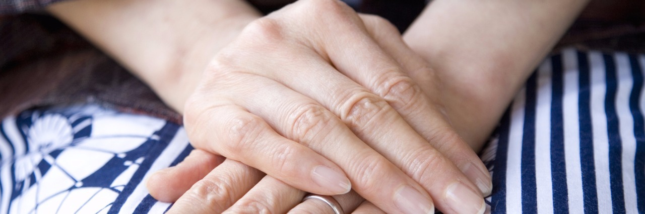 Woman's hands folded in lap, with one hand over the other