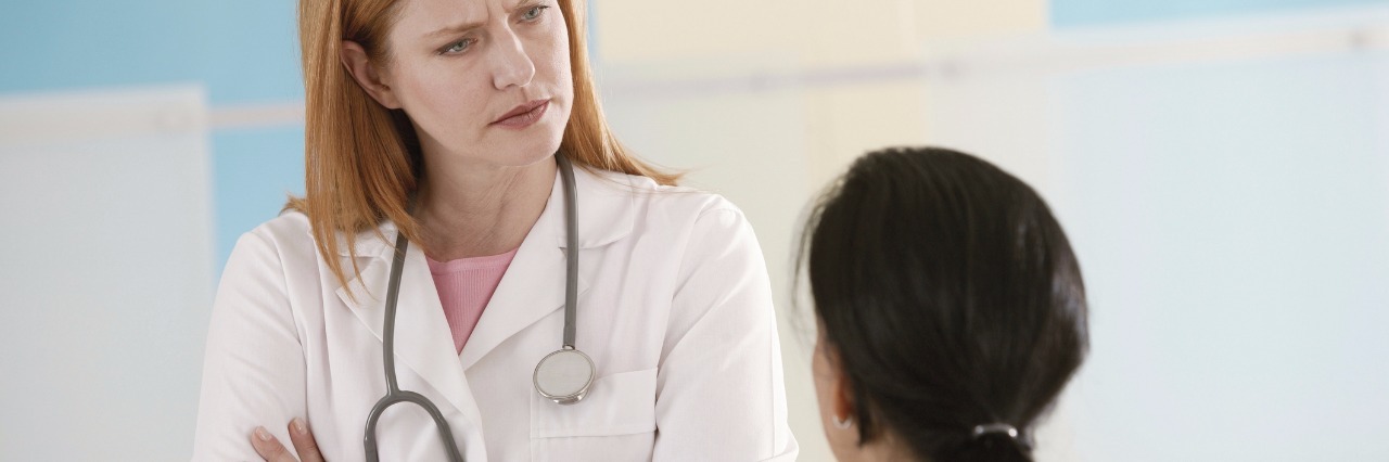 How to Cope With Discouraging Doctors When You Have a Rare Disease a doctor with her arms crossed facing a patient