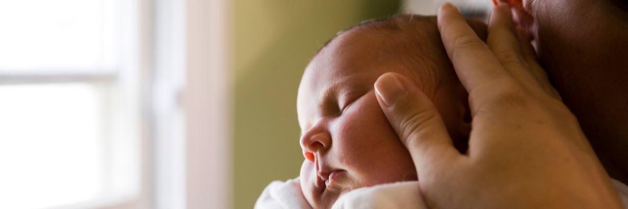 Deciding If I Should Have a Baby Despite My Chronic Illnesses Close-up of a young woman holding her baby