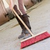 Woman sweeping stable.