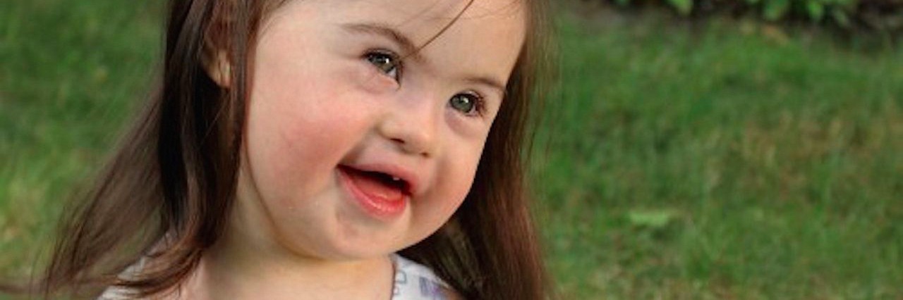What I Want You to Know During Down Syndrome Awareness Month little girl in dress sitting outside