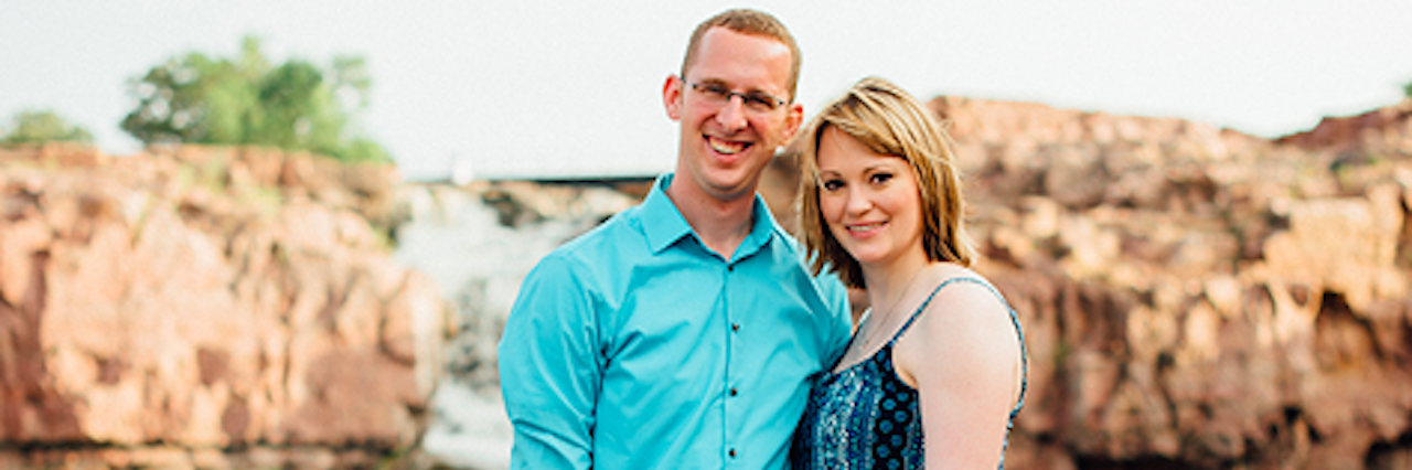 How Plan a Wedding When You Live With an Anxiety Disorder Wedding photo of a woman, her fiance and dog outdoors in front of a river.